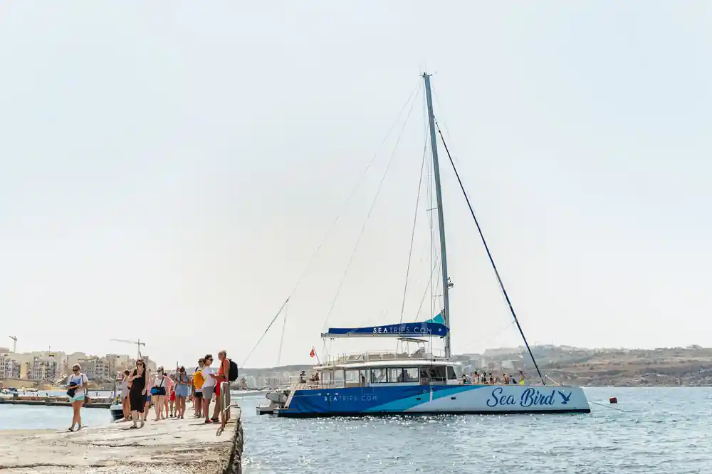 The catamaran alongside a quay with a queue of passengers waiting