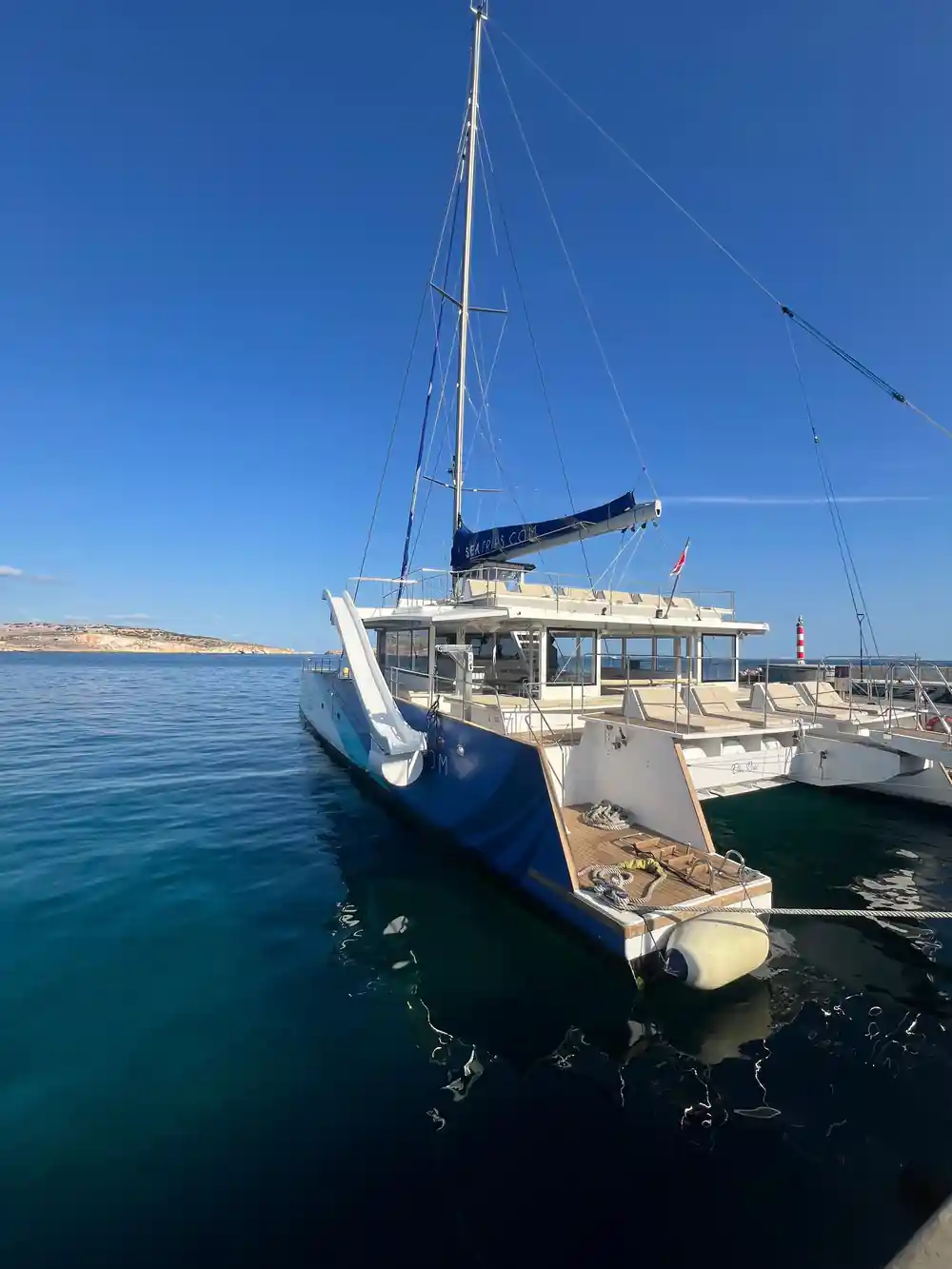 A catamaran lying quietly at anchor in flat evening water
