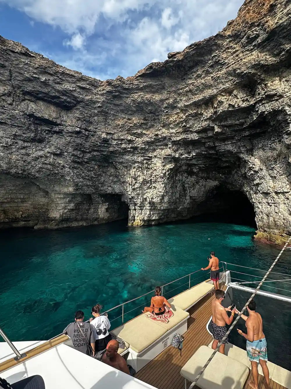 A cave entrance beside the boat with passengers on the foredeck