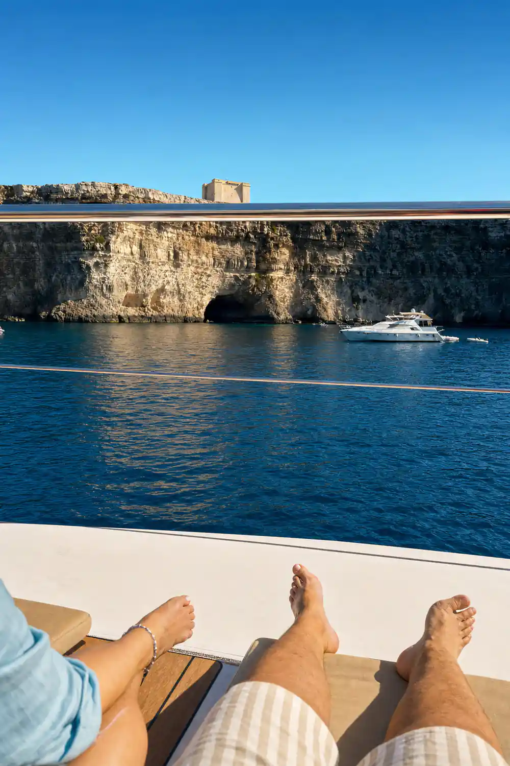 Cliffs with dark cave mouths at the waterline, seen over the bow