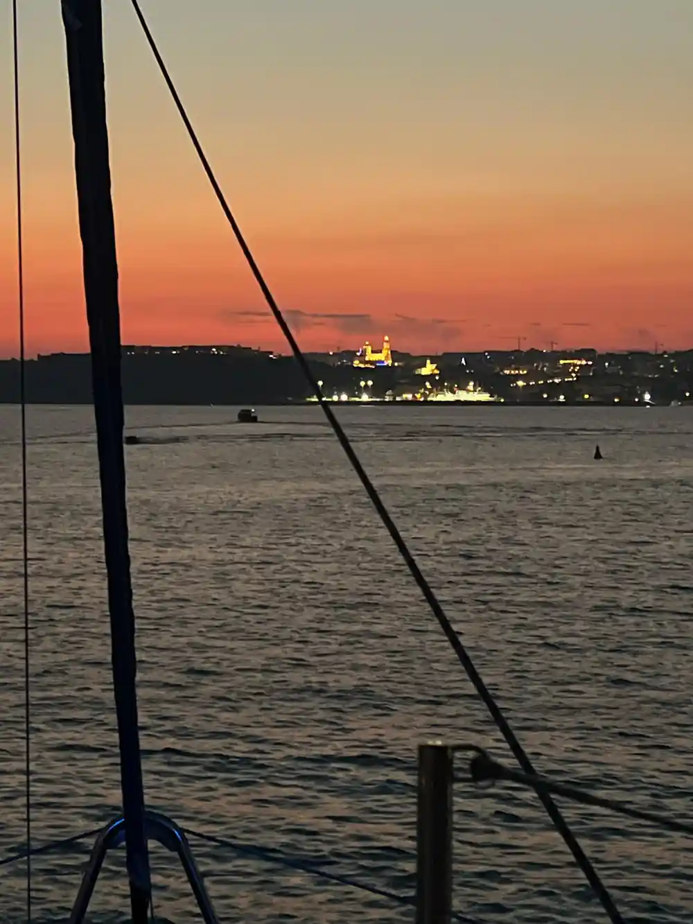 Dusk over the water with the lights of a hilltop town coming on