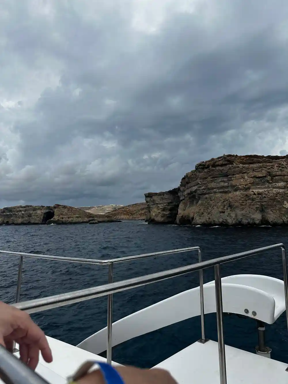 A flat-topped rock stack under grey cloud, seen over the rail