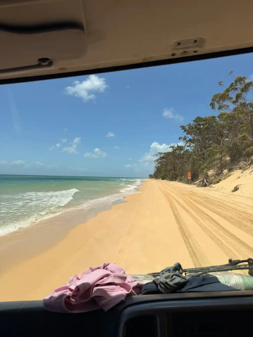 A long sandy beach and shallow water seen from the boat
