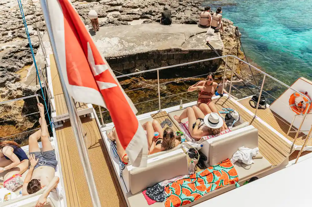 A red and white flag over the deck with passengers sunbathing beneath it