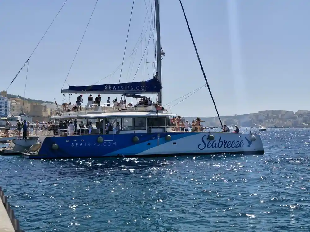 A second catamaran of the same fleet at anchor, deck full of passengers