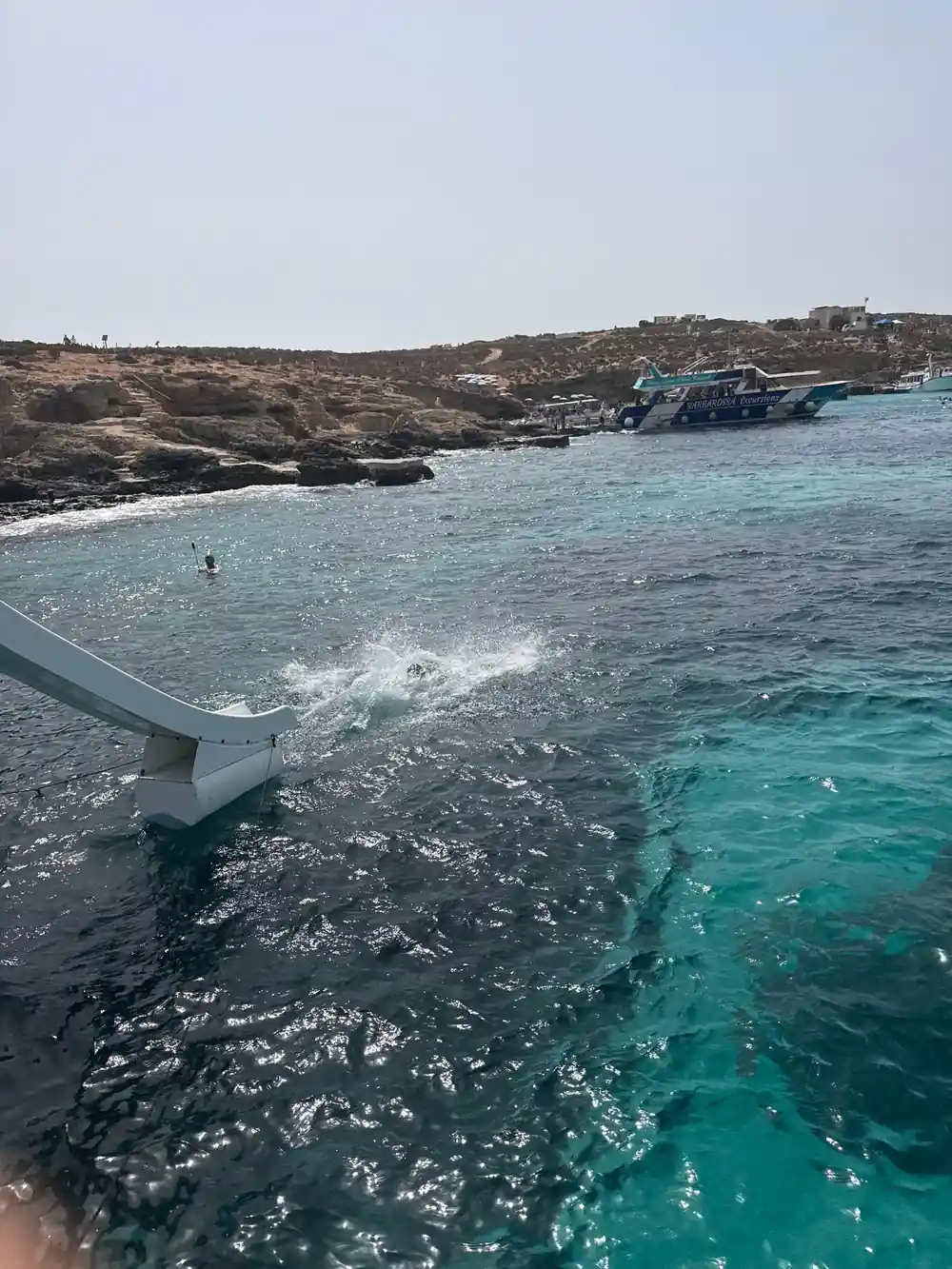 A slide from the boat's deck ending in the sea beside a low coast