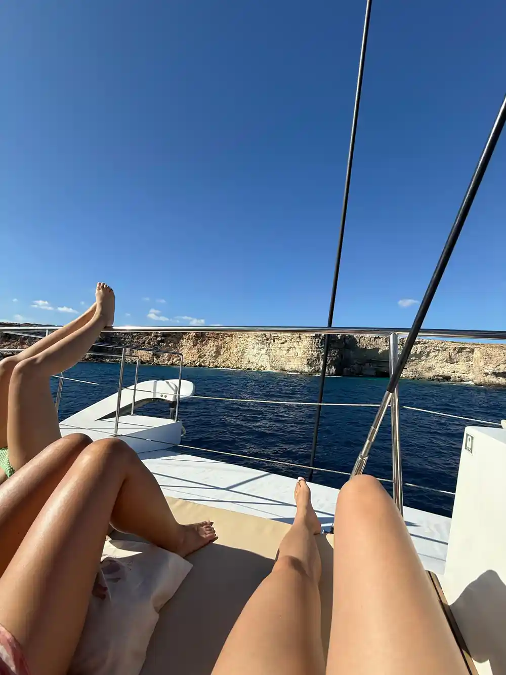 Sunbathers' legs on the foredeck with open sea beyond