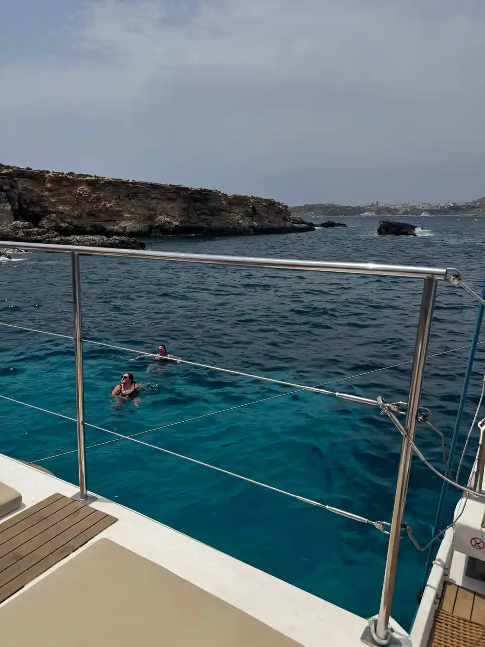 A swimmer alongside the hull with a rock stack on the horizon