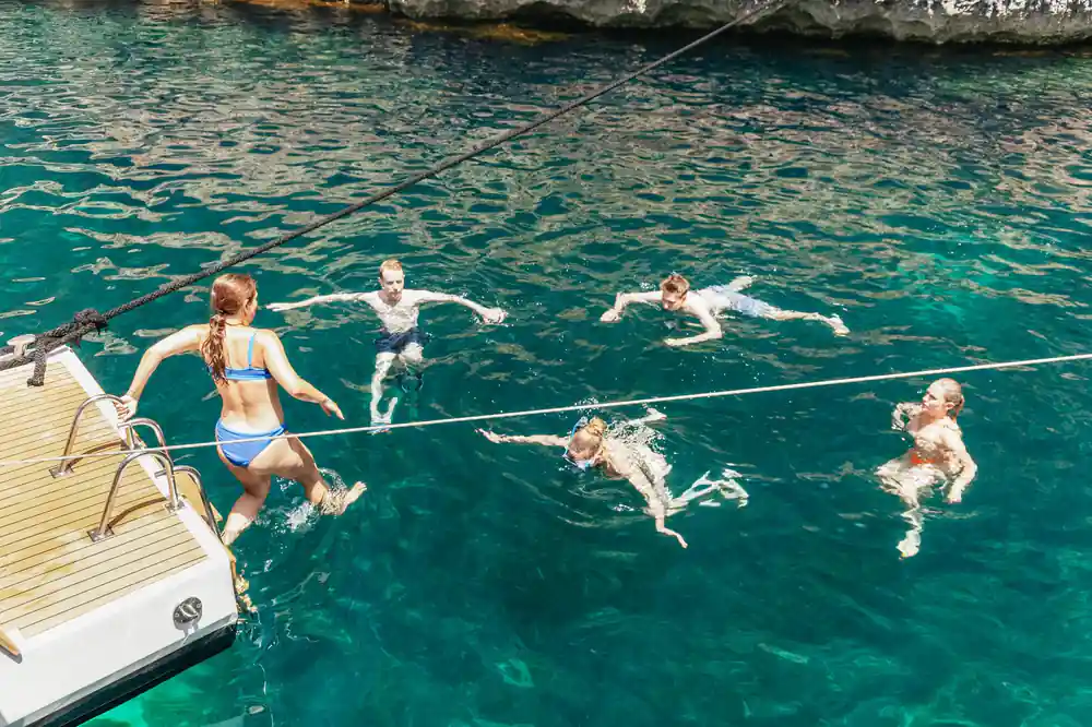 Swimmers in the water beside the hull on a calm day
