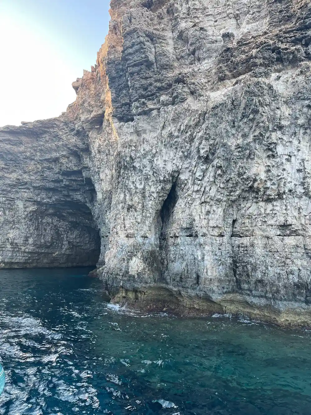 A tall pale cliff face streaked with weathering above dark water