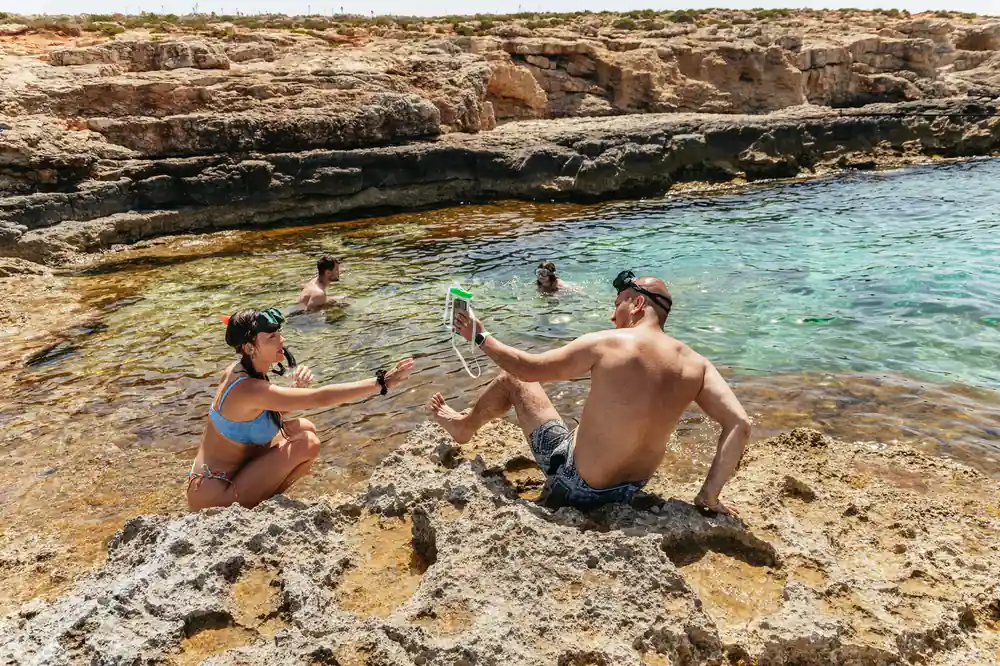 Two swimmers resting on rock at the edge of a clear inlet