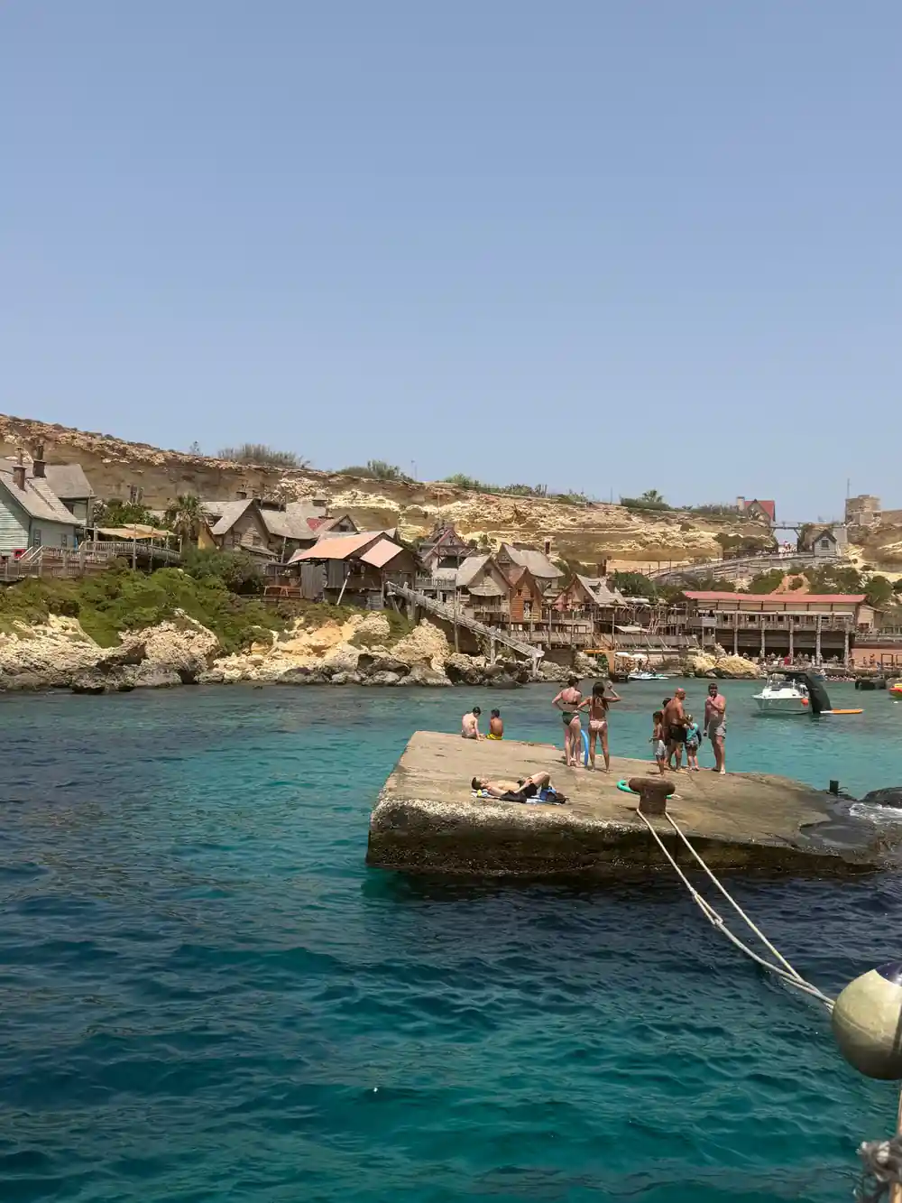 The wooden village above its small stone jetty with swimmers below