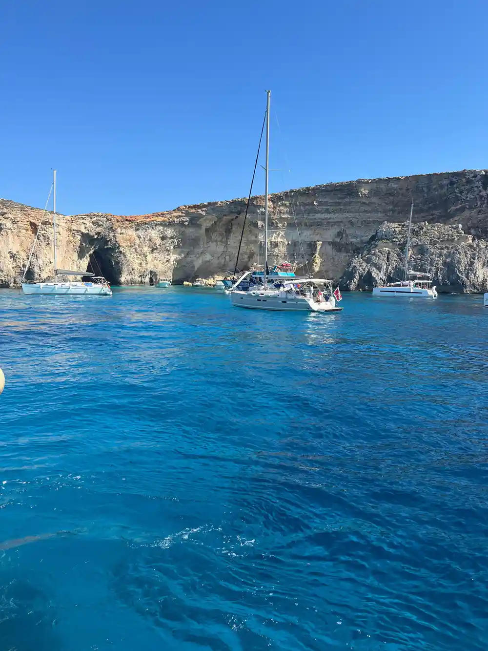 Yachts anchored in a cliff-ringed inlet of deep blue water